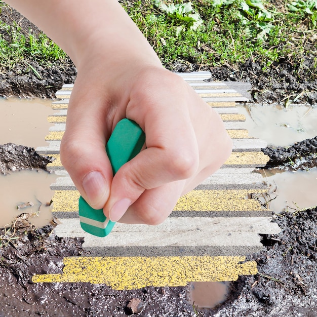 Hand deletes wet road from image by rubber eraser