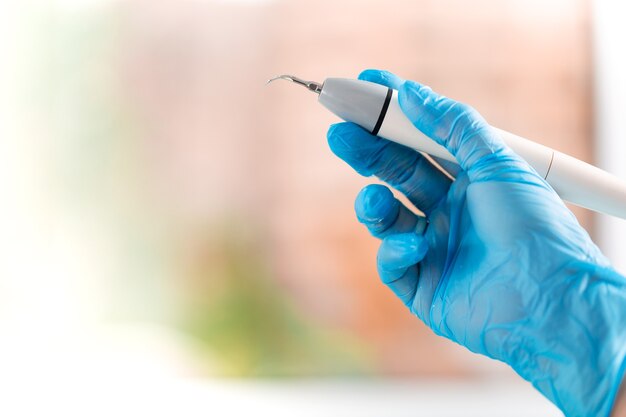 Hand of a dentist in a glove with a tool in his hands close-up.