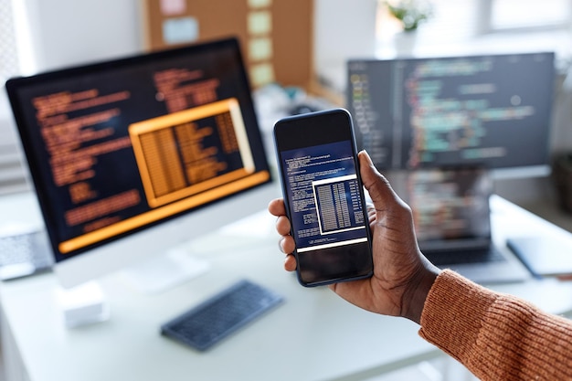 Photo hand of developer showing smartphone with code of new app on screen