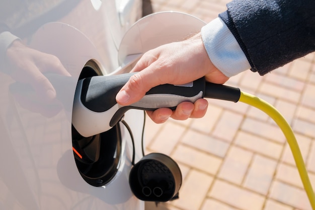 Hand die de stroomkabel in de elektrische auto steekt om op te laden