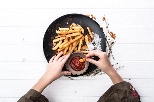 Hand die een aardappelchips in tomatenketchup dompelt