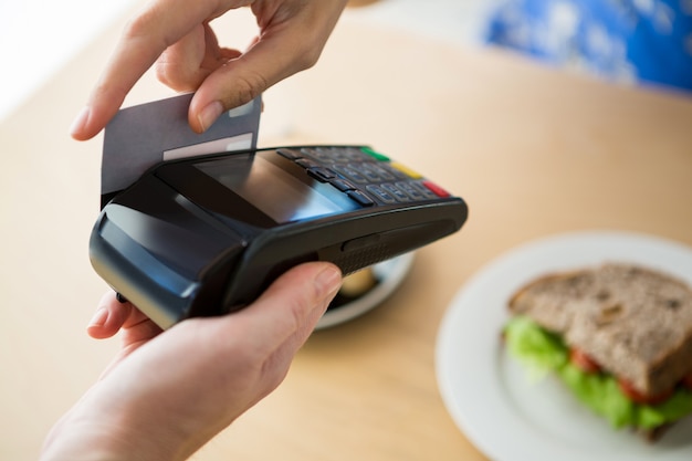 Hand die een creditcard naast de digitale tablet in de koffiewinkel houdt