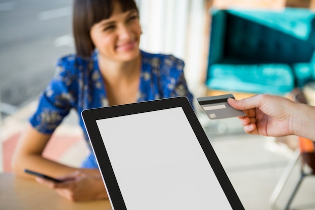 Hand die een creditcard naast de digitale tablet in de koffiewinkel houdt