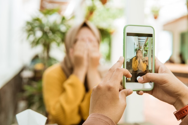 Hand die een foto van een gesluierd meisjes dicht gezicht met hand neemt die een smartphone gebruikt