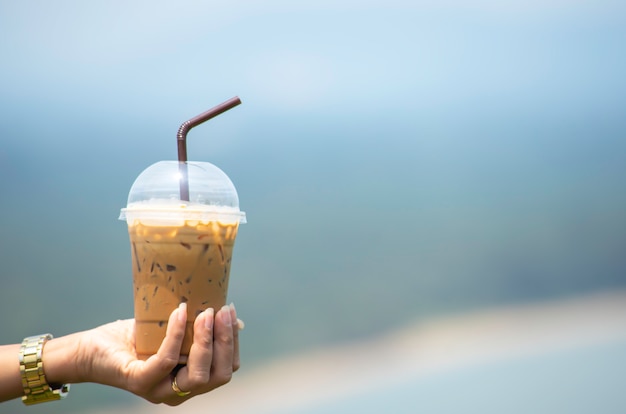 Foto hand die een glas koude espresso koffie en water als achtergrond onscherpe meningen houden.