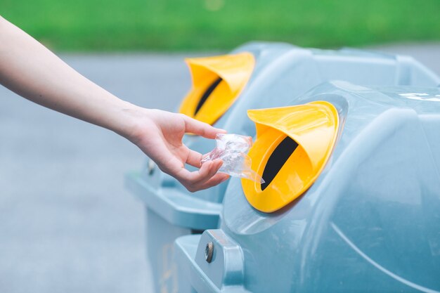 Hand die een plastic zak werpt in de bak.