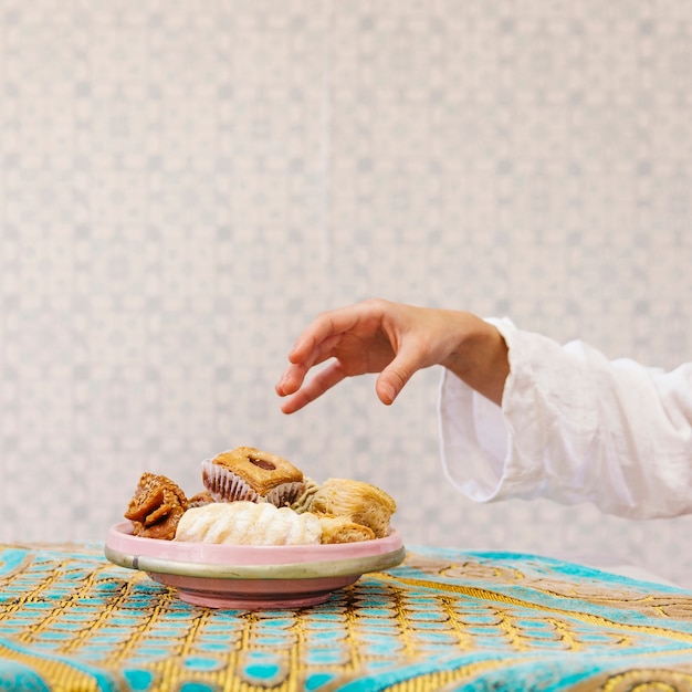 Foto hand die stuk van arabisch gebakje neemt