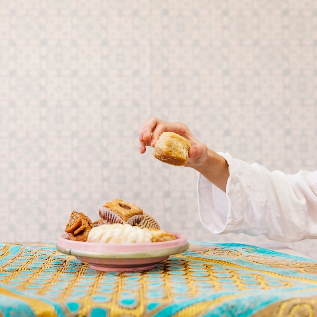 Foto hand die stuk van arabisch gebakje neemt