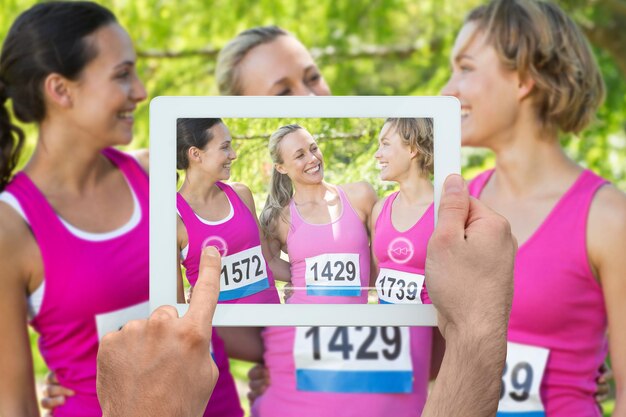 Foto hand die tablet-pc vasthoudt tegen lachende vrouwen die zich inzetten voor de bewustwording van borstkanker