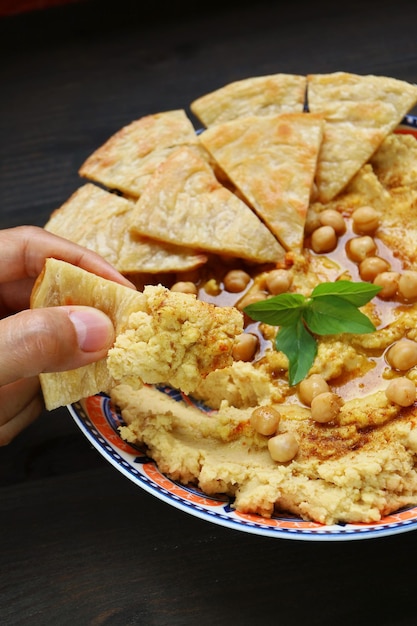 Hand Dipping Mouthwatering Hummus with a Piece of Pita Bread