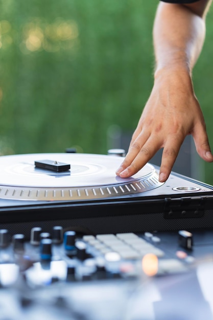 Hand of a DJ touching the turntable of the mixing console