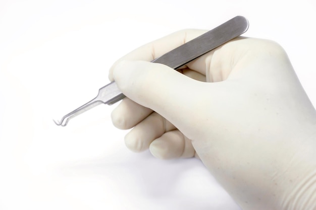 Hand of doctor holding a blackhead forceps remover isolate on white background and make with path