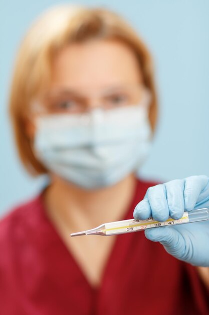 Hand of doctor in latex glove holding a glass mercury thermometer Selective focus on a thermometer