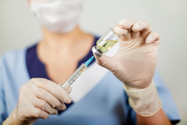 Hand of a doctor or nurse in nitrile gloves with a syringe needle