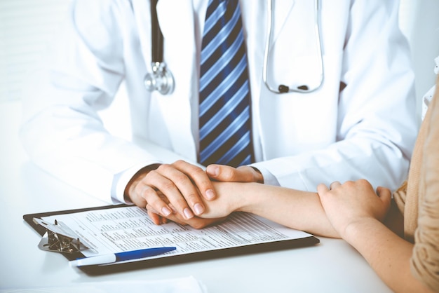 Hand of doctor reassuring her female patient. Concepts of medical ethics and trust in medicine.