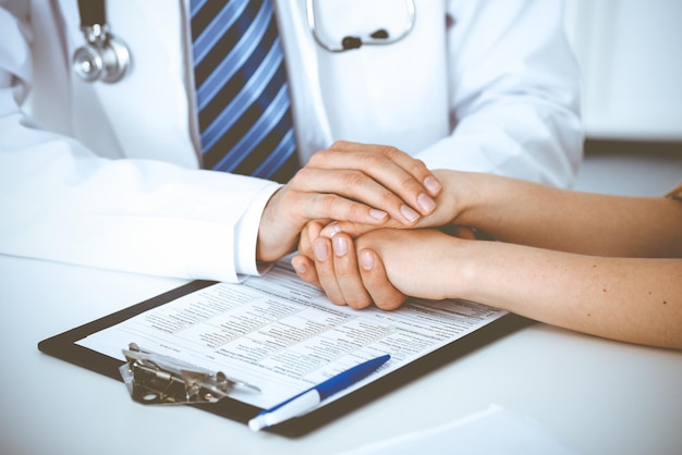 Hand of doctor reassuring her female patient. Concepts of medical ethics and trust in medicine.