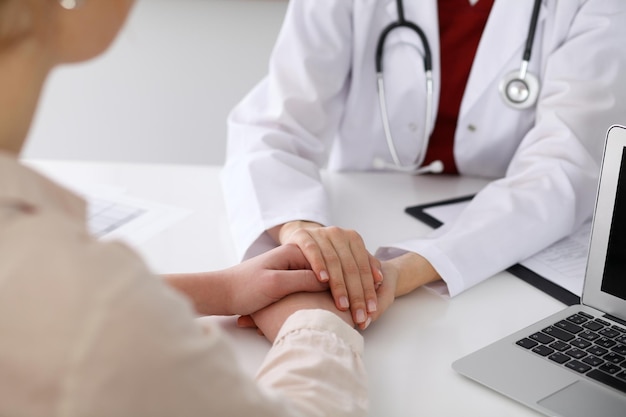 Hand of doctor  reassuring her female patient. Medical ethics and trust concept