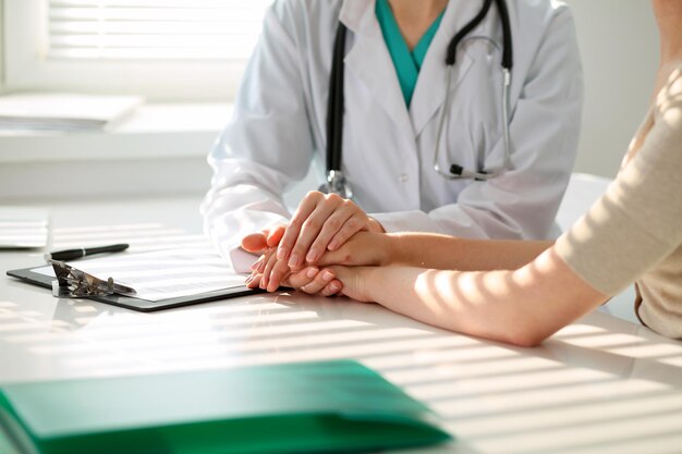 Hand of doctor  reassuring her female patient. Medical ethics and trust concept