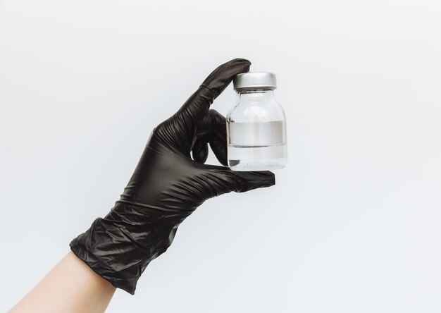 Photo in the hand of a doctor in rubber gloves an ampoule with a vaccine closeup and free space for text