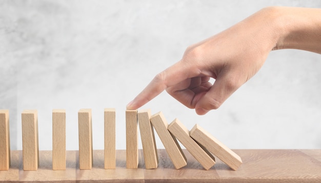 Hand and Domino effect stopped with a finger