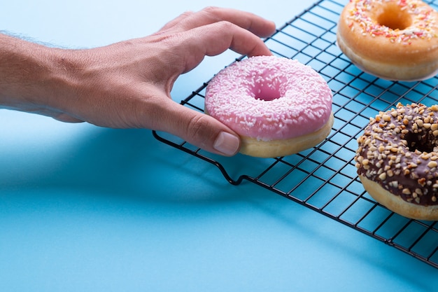 Hand donuts krijgen op blauwe achtergrond.