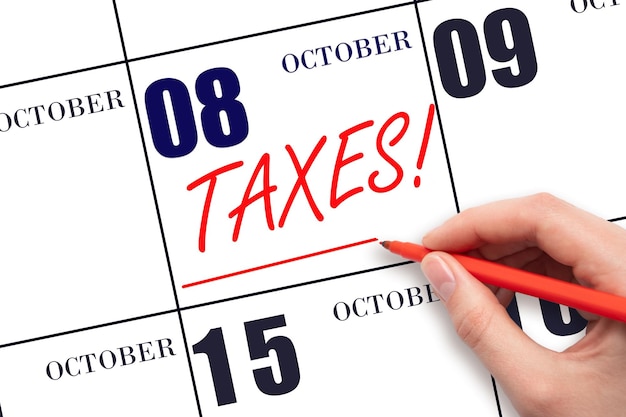 Hand drawing red line and writing the text Taxes on calendar date October 8 Remind date of tax payment