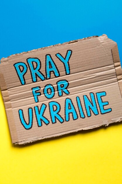 Hand drawn poster with slogan Pray For Ukraine on Ukrainian flag