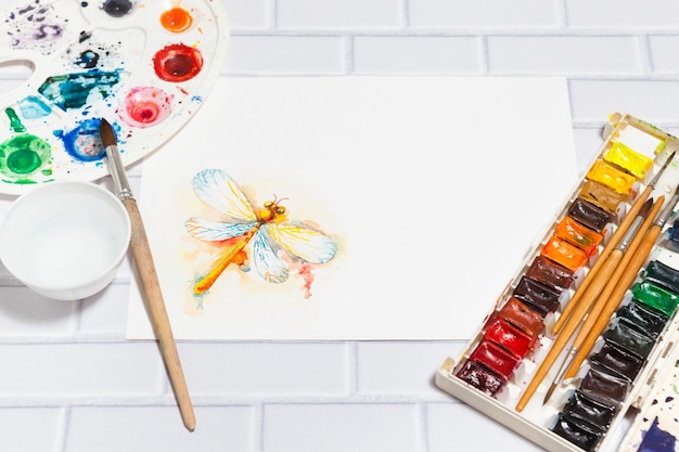 Hand Drawn watercolor Dragonfly Sketch paints paintbrushes palette concept of human creativity