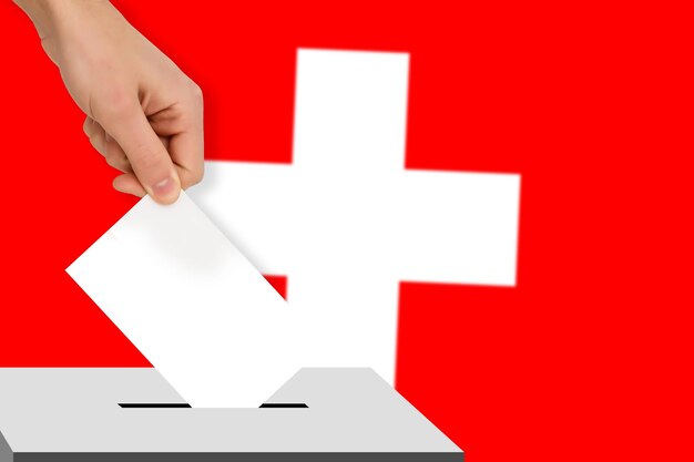 Hand drops the ballot election against the background of the switzerland flag concept of state elections referendum