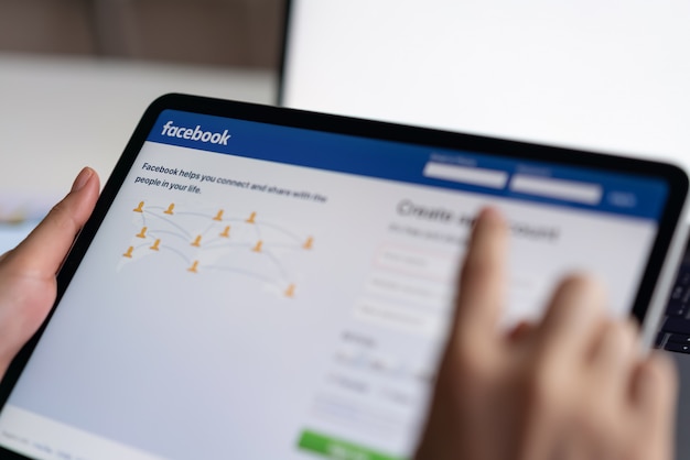 Hand drukt op het facebook-scherm op tablet