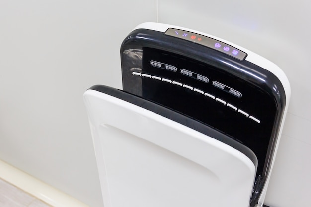 Hand dryer hanging on the public restroom gray wall 