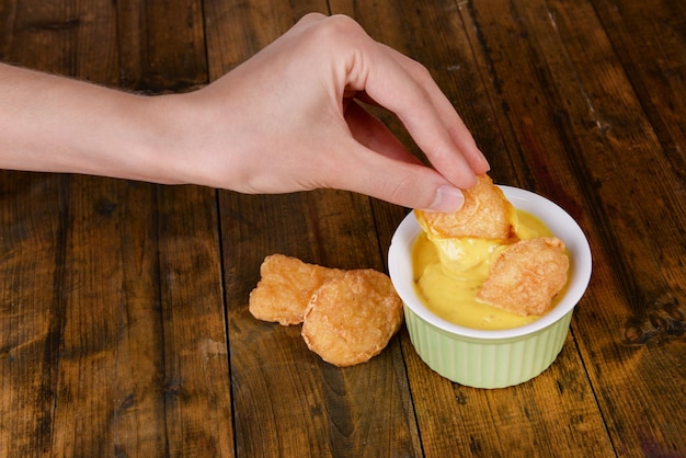 Photo hand dunks nuggets in sauce closeup