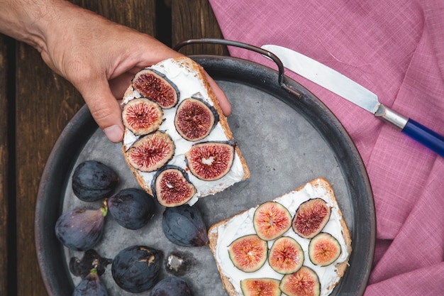 Hand eating ricotta sandwich with fresh figs
