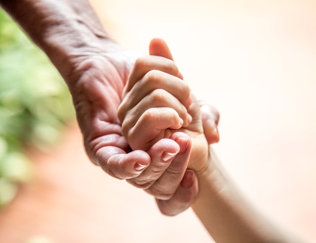 Foto mano di una donna anziana che tiene la mano di un bambino