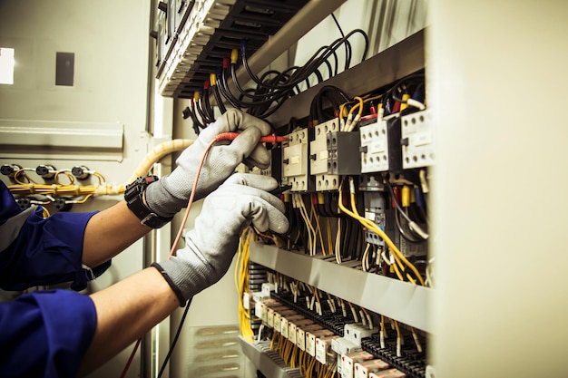 Hand of electrical engineer checking electric current voltage at circuit breaker terminal