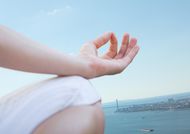 Hand en knie van mediterende vrouw tegen kustlijn