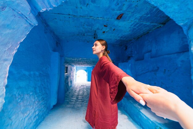 The hand entering the frame holds the hand of the girl leaving the tunnel in the blue city. Morocco