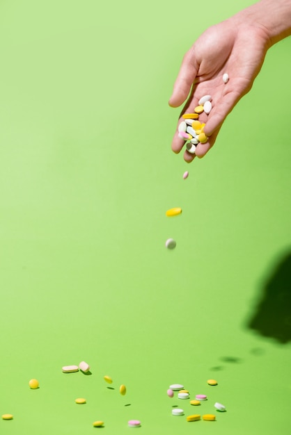 A hand falls medicine pills over green background