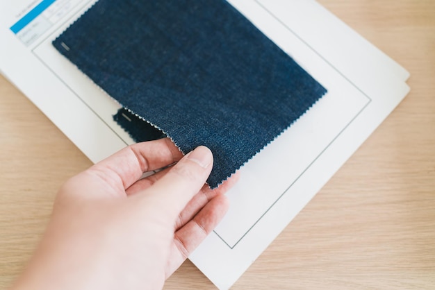 Hand of a fashion designer or tailor touching and feeling the texture of sample blue color fabrics textile Selection of dressmaker for designing new clothing collections in an atelier