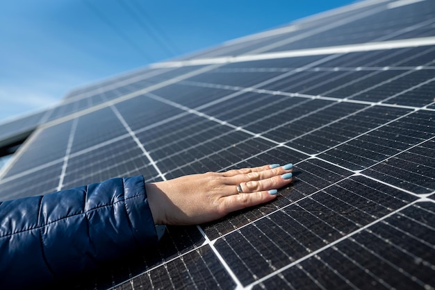 Hand of female engineer checking solar operation cleanliness of\
photovoltaic solar panels sun