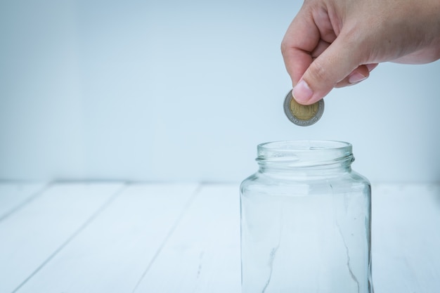 Hand filing coin into the empty glass bottle