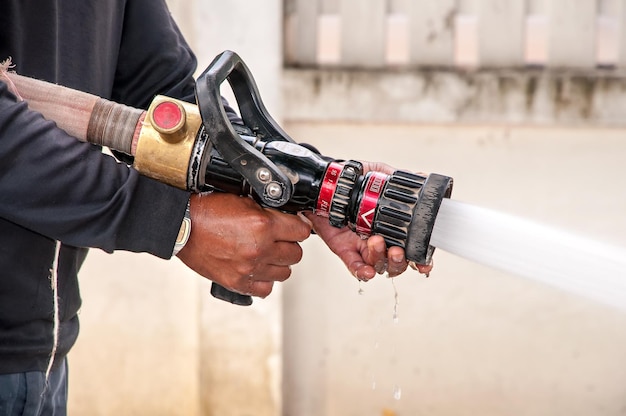 Photo hand of firefighter at works with water cannon