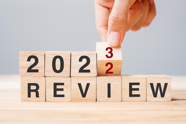 Hand flipping block 2022 tot 2023 REVIEW tekst op tafel Resolutie idee doel motivatie reboot business en Nieuwjaar vakantie concepten