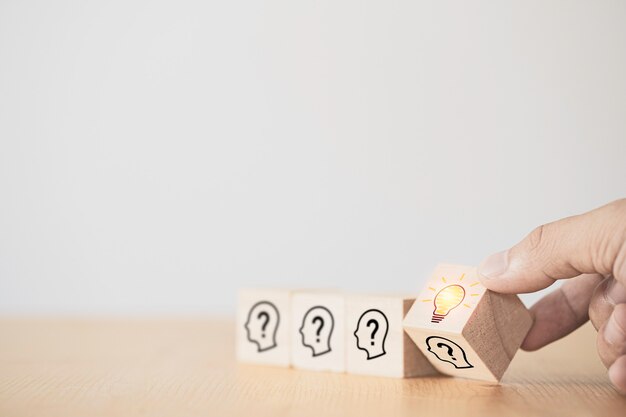 Blocchetto di cubo di legno che gira a mano che stampa la faccia dello schermo con punto interrogativo a lampadina