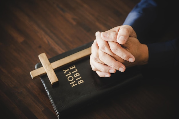 Hand folded in prayer to god on Holy Bible book in church concept for faith spirituality and religion woman person praying on holy bible in morning christian catholic woman hand with Bible worship