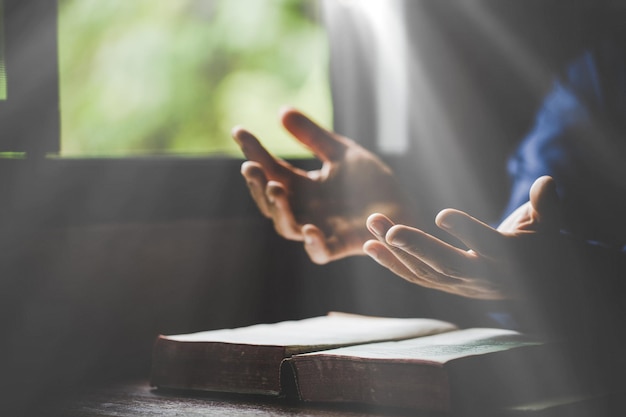 Hand folded in prayer to god on holy bible book in church\
concept for faith spirituality and religion woman person praying on\
holy bible in morning christian catholic woman hand with bible\
worship