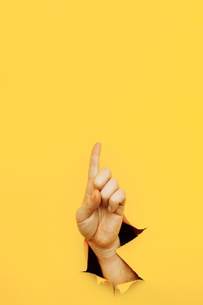 Hand forefinger indicating of the direction isolated on yellow background.