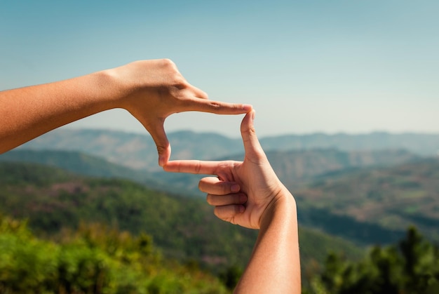 Hand framing view distant over sunset on mountain