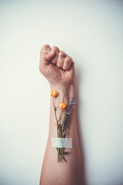 Hand gebalde tot een vuist met bloemen. Tienerproblemen, ongeneeslijke ziekten, sociale relaties, het concept