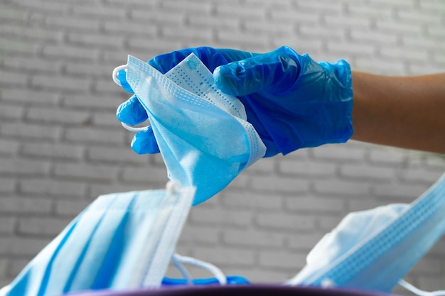 Hand gebruikt vuile chirurgische masker in een vuilnisbak brengen.